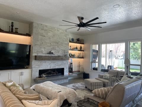 Painted living room with a stone fireplace, white walls, and trim